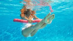 a woman is floating in the water with a red tube attached to her back and feet