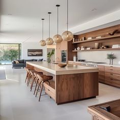 a modern kitchen with wooden cabinets and hanging lights over the island countertop, along with bar stools