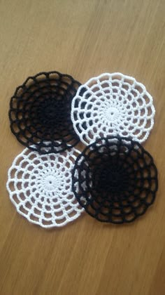 three crocheted coasters sitting on top of a wooden table