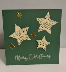 a green christmas card with gold stars and sheet music