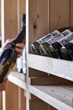 a person holding a bottle of wine in front of some shelves with bottles on them