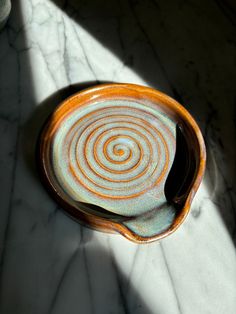 an orange and blue bowl sitting on top of a marble counter