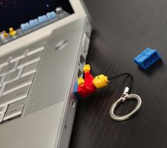 a lego man keychain sitting on top of a laptop computer next to a lego figure