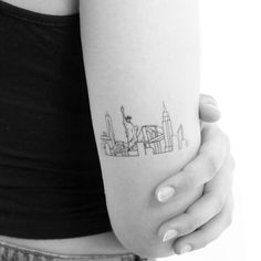 a woman's arm with a small city skyline tattoo on the left inner arm