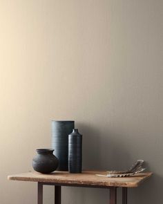 two black vases sitting on top of a wooden table