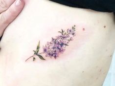 a close up of a woman's stomach with purple flowers on the side and green leaves