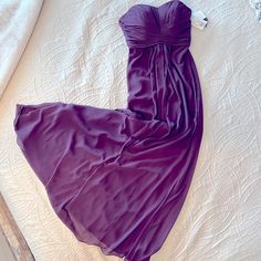 a purple dress laying on top of a bed