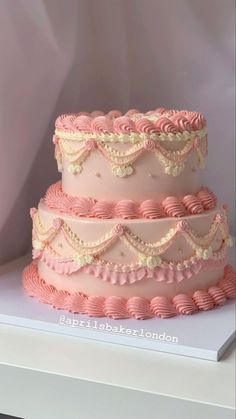 a three tiered cake with pink icing and ruffles on the sides