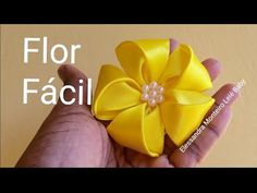 a hand holding a small yellow flower with pearls in the center and text that reads, flor facii