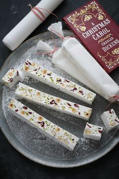 four pieces of white chocolate sitting on top of a glass plate next to a book