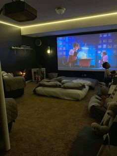 two people sitting in front of a projector screen while watching movies on the couches