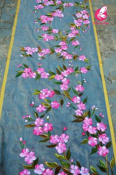 a blue table runner with pink flowers painted on it and yellow trim around the edges