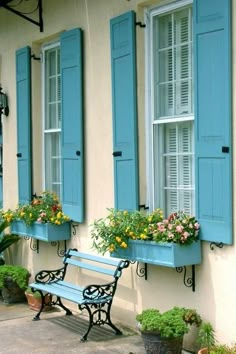 blue shuttered windows with flower boxes and bench in front