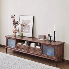 a wooden entertainment center with two drawers and three candles on the shelf next to it