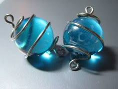 two blue glass balls with silver wire wrapped around them