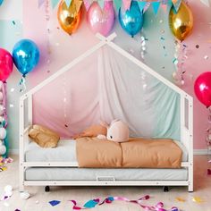 a child's bed with balloons and streamers on the wall