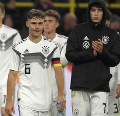 two soccer players are standing next to each other and one is holding a water bottle