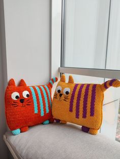 two knitted cats sitting on top of a chair