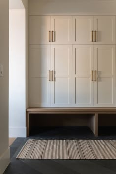 an empty room with white cabinets and striped rug