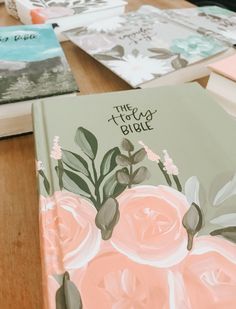 several books with flowers painted on them sitting on a table