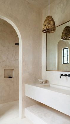 a bathroom with two sinks and an arched doorway leading to the shower area is shown