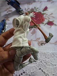 a hand holding a small figurine with a stick in it's mouth