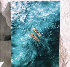 two kayaks floating in the ocean on top of blue green water with foamy waves