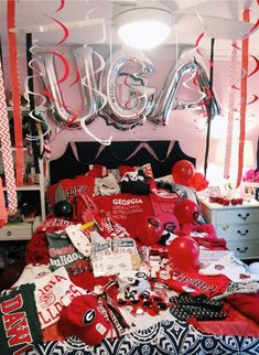 a bed with red and black sheets, balloons and other items on top of it