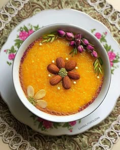 a bowl filled with food sitting on top of a white and pink plate next to a doily