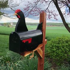 a mailbox in the shape of a chicken with a red head and black body