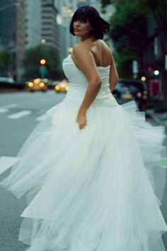 a woman in a white dress is walking across the street