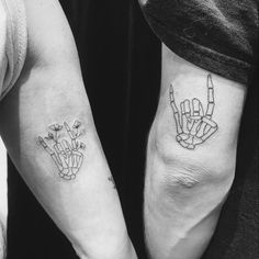 two people with tattoos on their arms holding hands and pointing fingers at the same direction