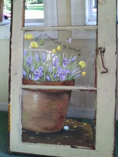 a potted plant with purple and yellow flowers is painted on an old window frame