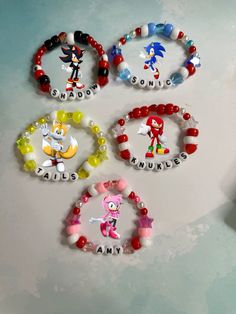 four bracelets with cartoon characters on them sitting on a table next to each other