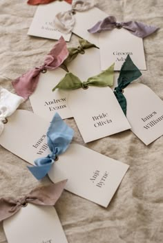 several different types of bows are laid out on the bed sheet with name tags attached to them