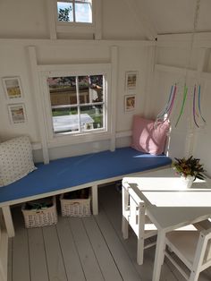 a room with white walls and wooden flooring has a blue cushion on the bench