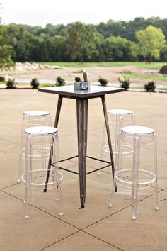 four stools and a table with bottles on it in the middle of a patio