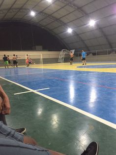 people are sitting on the floor in an indoor basketball court