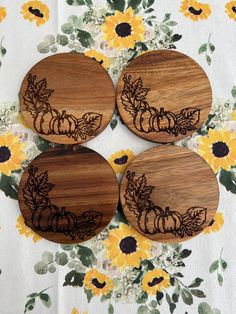 four wooden coasters decorated with pumpkins and sunflowers on a tablecloth