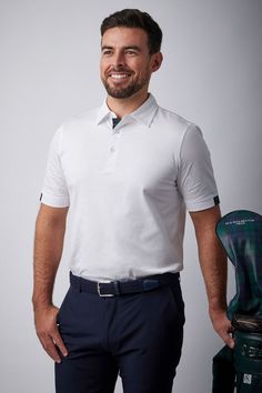 a man in white shirt and blue pants holding a green golf club headcover