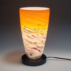 an orange and white glass vase sitting on top of a table next to a charger