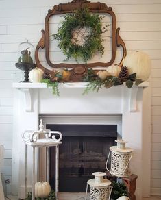 a fireplace decorated with white pumpkins and greenery