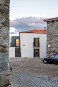 a black car parked in front of a white building on a cobblestone street