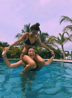 two women in bikinis are jumping into a pool