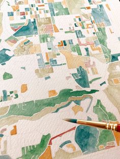 a watercolor map is shown with a brush resting on it's edge,