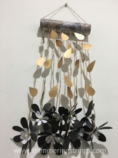 a metal wind chime hanging from a rope with leaves and flowers attached to it