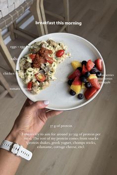 a white plate topped with food next to a bowl of fruit