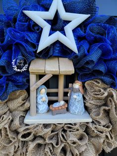 a nativity scene is displayed in front of a blue wreath with white stars on it