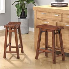 two wooden stools sitting next to each other in front of a kitchen counter top