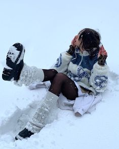 a woman is sitting in the snow with her feet up and wearing knee high socks